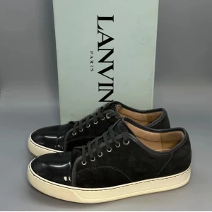 Svarta lanvin cap toe  - ❗️BOX INGÅR EJ❗️ Snygga svarta lanvin sneakers med cool lackad tå och ovandel i mocka. Bilderna är ifrån när jag köpte de som var 3 mån sen. Skorna är i storleken uk 6 som motsvarar 40-41. Skorna har snörning och en beige platt sula som ger en klassisk vibe. Perfekta för dig som gillar stilrena detaljer och vill sticka ut med en unik look. De är i ganska bra skick,skriv till mig vid minsta fundering.❗️Box ingår ej ❗️. De första bilderna är ifrån när jag köpte de.😃💸 Mvh Emil