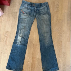 Blå bootcut jeans från Diesel  - Snygga blå bootcut jeans från Diesel med slitningar och ljus tvätt. Klassiska femficksdetaljer, låg midja och coola kontrastsömmar. Tillverkade i Italien i mjukt jeanstyg, perfekta för en avslappnad och trendig look. SÅ SNYGGA, för små för mig tyvärr, storlek 25!🩷
