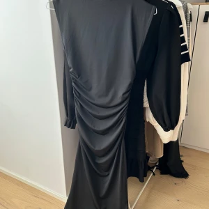 Svart midiklänning med drapering - Midi klänning som sitter tight. Storlek XS från Hm. Sitter fint! Klippt lapparna men aldrig använt! 