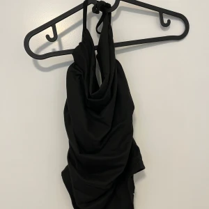 Svart halterneck  - Snygg svart halterneck och knyt i nacken. Enkel och stilren design som passar perfekt för svartare väder. Mjuk och följsam passform som känns bekväm hela dagen.