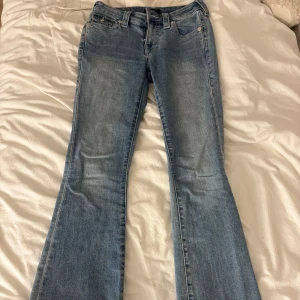 True Religion ljusblå bootcut jeans - Säljer ett par ljusblå bootcut jeans från True Religion med snygga kontrastsömmar och ikoniska fickdetaljer bak. Modellen är mid rise och har klassisk femficksdesign, dragkedja och knapp framtill. Perfekta för dig som gillar en avslappnad men trendig look💓. Skriv för mått och pris kan diskuteras💓💓storlek 24 Becca 