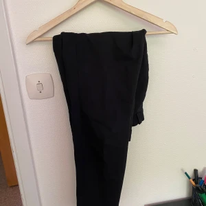 Svarta byxor i bomull - Svarta byxor i mjukt bomullsmaterial. Klassisk rak passform med enkel design, perfekta för en clean och stilren look. Passar till det mesta och är lätta att matcha med olika outfits.