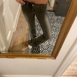 Grå Weekday  bootcut jeans - Säljer ett par gråa jeans från Replay med bootcut passform. Jeansen har låg midja, klassiska fem fickor och en snygg tvättad look. Materialet är jeans och de har en grön Replay-etikett bak i midjan. Perfekta för dig som gillar en avslappnad men trendig stil.