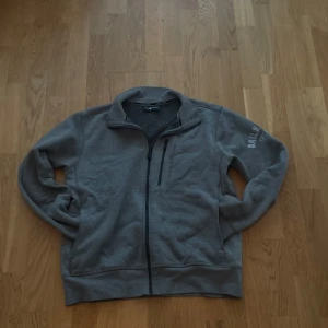 Jacka grå sail racing fleece - Denna grå Sail Racing-fleecejacka har hel dragkedja och broderad logga på ärmen. Den verkar vara i gott skick utan synliga skador.  ⭐️ Skick: 8/10 🎨 Färg: Grå 📦 Snabb och trygg frakt