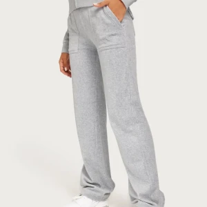 Grå mjukisbyxor juicy  - Snygga grå mjukisbyxor med raka ben och bekväm passform. Byxorna har bred resår i midjan och praktiska fickor framtill. Perfekta för en chill och avslappnad stil.