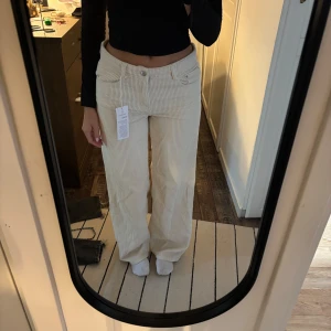 Lågmidjade vita manchesterbyxor Gina Tricot - Säljer ett par vita manchesterbyxor från Gina Tricot i modellen low wide cord. Byxorna har låg midja och breda ben, med klassiska fickor fram och bak. Perfekta för dig som gillar en avslappnad och trendig look. Helt nya kostar i butik 499kr
