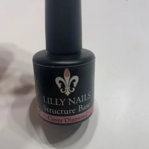 Lilly Nails Structure Base Cover Diamond - Lilly Nails Structure Base i nyansen Cover Diamond, gelébas för naglar. Kommer i en svart flaska med penselapplikator. Perfekt för att bygga upp och stärka naglarna innan färg eller design.
