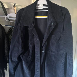 Mörkblå  manchester overshirt från Vailent - Säljer en mörkblå overshirt från Vailent i mjuk manchester. Skjortan har en stor bröstficka, bred krage och knappar framtill. Perfekt att slänga över en t-shirt för en chill look. Oversized passform för extra skön vibe.