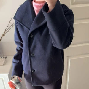 Mörkblå skepparkavaj med stora slag - Säljer en stilren mörkblå skepparkavaj med stora slag och tre knappar framtill. Jackan har en klassisk rak passform och är tillverkad i ett tjockare material som känns mjukt och värmande. Perfekt för dig som gillar en clean och tidlös look. Använde lite förra  vinter, annars som ny inga effekter, super fin💕