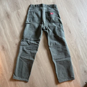 Gröna/grå cargopants från Dickies, stl 32 - Säljer ett par gröna cargopants från Dickies i storlek 32. Byxorna har raka ben, flera praktiska fickor på sidorna och bak, samt klassisk Dickies-logga på bakfickan. Köpta från Beyond Retro på Södermalm. Jag är 189 och skulle säga att jag är precis för stor för dem.