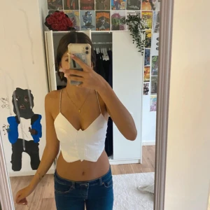 Vit croppad linnetopp med strassband - Säljer en vit croppad linnetopp från FB Sister i storlek XXS. Toppen har tunna axelband med strassdetaljer som korsas i ryggen och knyts baktill. Djup v-ringning framtill och figurnära passform. Perfekt för dig som gillar trendiga och snygga toppar.
