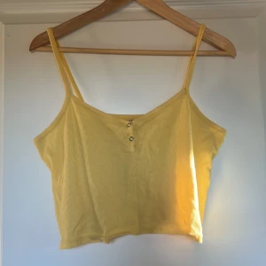 Gul ribbad linnetopp med knappar - Snygg gul croppad linnetopp från Gladpeer Apparel. Den är ganska kort och står ingen storlek men skulle säga att den är L/XL