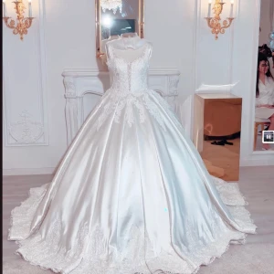 Vit prinsessklänning med spetsdetaljer - Drömmig långklänning i vit satin med vacker spets upptill och längs kjolkanten. Klänningen har djup v-ringning, breda axelband och en riktigt maffig kjol med släp. Perfekt för dig som vill känna dig som en prinsessa.