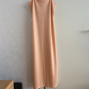 Mönstrad midiklänning från Zara - Säljer en  klänning från Zara i mjukt material med orange och vitt rutmönster. Klänningen har rak passform. Perfekt för dig som gillar färg och mönster!