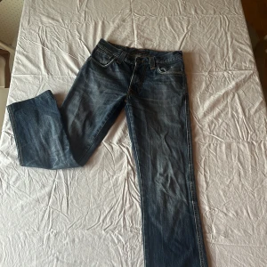 Blå jeans från Nudie Jeans, W29 L32 - Snygga blå jeans från Nudie Jeans i klassisk modell med raka ben och orangea sömmar. Perfekta för dig som gillar stilrena och tidlösa jeans med schysst passform.