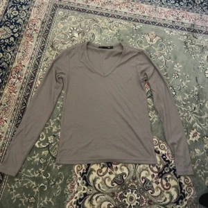 Beige ribbad långärmad tröja 157 - Säljer en beige ribbad långärmad tröja från 157 med v-ringad hals. Tröjan är i mjukt material och har en enkel, stilren design som passar perfekt till jeans eller kjol.