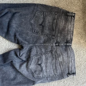 Svarta slim fit/raka jeans - Svarta  jeans med rak passform och klassisk femficksdesign. Jeansen har en mörk tvätt och tydliga sömmar, tillverkade i slitstarkt jeanstyg. Perfekta för dig som gillar en tidlös och clean look.