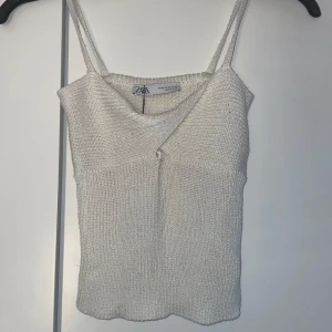 Vit stickad linnetopp - Supersnygg vit stickad linnetopp från Zara med smala axelband och lätt omlott-detalj framtill. Prislappen är kvar