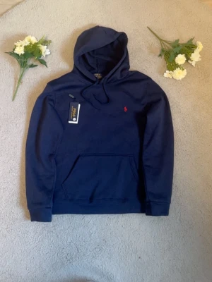 Ralph lauren hoodie i navyblå  - Jag säljer en snygg och ny Ralph Lauren hoodie i navyblå färg, perfekt för både vardag och träning! Hoodien är i storlek S och kommer med taggarna kvar, så den är använd ett par gånger. Den är både bekväm och stilren, vilket gör den lätt att matcha med både jeans och träningsbyxor. Jag vill också poängtera att jag är aktiv och snabbt skickar hoodien samma dag eller dagen efter köpet, så du kan få din nya favoritplagg på nolltid! Passa på att köpa denna kvalitetsprodukt till ett bra pris.