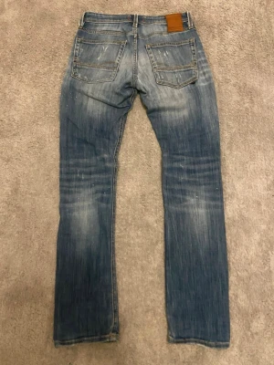 Jack and Jones Glenn jeans blåa - Säljer ett par blå jeans från Jack & Jones med passformen Glenn vilket är den populäraste, jeansen har snygga slitningar och trasiga detaljer framtill. Jag säljer dem pga att de inte passar längre. Storleken är w27 och l32 skicket är 8/10 och nypris är runt 1200kr. Om ni har några frågor så e det bara att skriva!