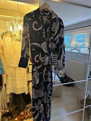 Mönstrad blå klänning med knytband - Snygg klänning i marinblått med vita och blåa blommor. 