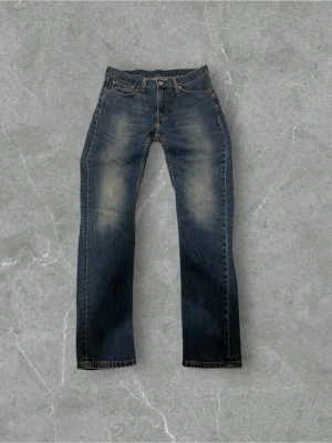 Levi's 511 mörkblå jeans W32 L32 - Säljer ett par Levi's 511 jeans i mörkblå tvätt med snygga slitningar på låren och knäna. Klassisk femficksmodell med Levi's patch bak och röd etikett på bakfickan. 