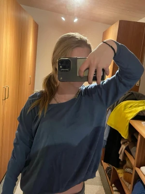 Blå loose långärmad tröja - Säljer en blå långärmad tröja med loose passform och offshoulder-stil. Tröjan är enkel och stilren, perfekt att slänga på sig till jeans eller mjukisbyxor. Materialet känns mjukt och bekvämt mot huden.