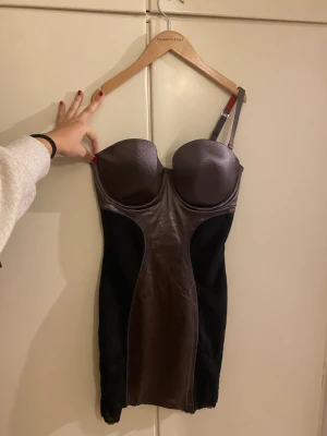brun polyamid intimklänning från Scandale - Brun kort intimklänning från Scandale i svart och brun med glansig finish och spetsdetaljer nertill. Strl står i nästsista bilden.