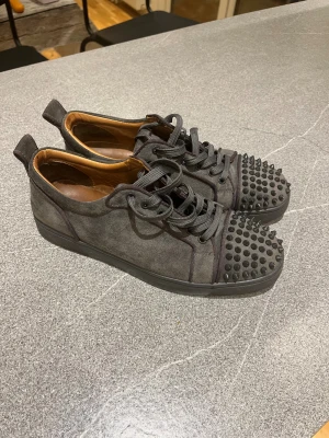 Christian Louboutin grå sneakers med nitar - Super snygga sneakers från Christian louibitin. Andvänd cirka 8 gånger och är i toppskick efter en tvätt, har bara inte haft orken att tvätta dem. Saknar 1 nit men är inget man tänker på vid andvändning.Pris är ej hugget i sten!🤩                                                           (Rep)