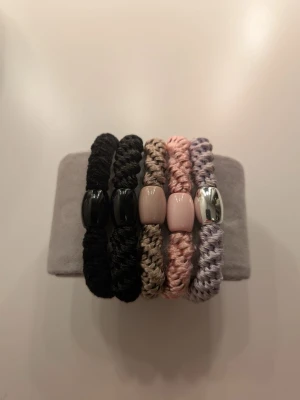 Set med fem tjocka hårsnoddar - Säljer ett set med fem tjocka hårsnoddar i olika färger: svart, brun, rosa och lila. Snoddarna är flätade och har en blank pärldetalj i mitten, två svarta, en beige, en ljusrosa och en silverfärgad. Perfekt att ha som armband eller använda som hårsnoddar. 💕 