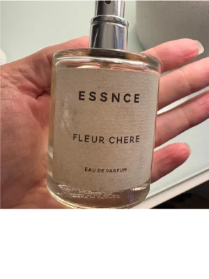 Essnce Fleur Chere EdP - Modern Eau de Parfum från Essnce med stilren design. Perfekt för dig som vill ha en unik doft i din samling. Flaskans etikett ger en minimalistisk känsla. Volym och ingredienser syns ej tydligt på bilderna.
