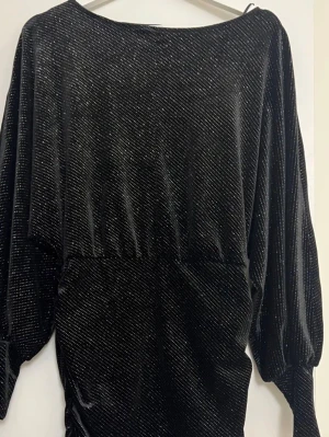 Nyårsklänning - Säljer en svart klänning med glittriga detaljer och lång ärm. Storlek S men stretchig och passar därför också storlek M. Använt en gång💕