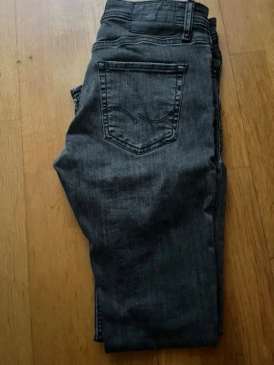  svarta jeans med rak passform - Säljer ett par svarta jeans från Replay med klassisk femficksdesign och snygga detaljer på bakfickorna. Jeansen har rak passform och är tillverkade i mjukt jeanstyg som sitter skönt hela dagen. Perfekt för dig som gillar stilrena och tidlösa jeans.