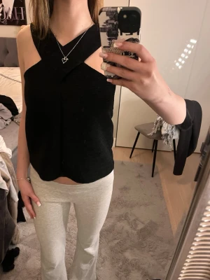 Svart omlott korsett-topp - Säljer en svart korsett-topp med omlott-detalj och breda axelband som korsar över bröstet. Endast använd några gånger.