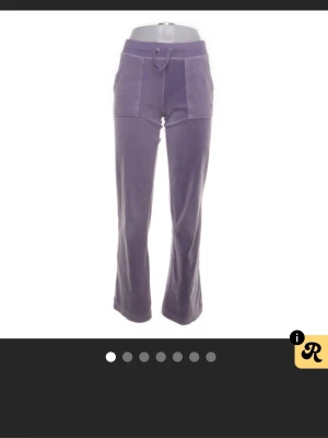 Lila mjukisbyxor Juicy Couture XS - Säljer ett par lila mjukisbyxor från Juicy Couture i storlek XS. Byxorna har bootcut-snitt, snörning i midjan och fickor både fram och bak med knappdetaljer. Materialet är mjukt och skönt, typiskt velour. Perfekt för chill dagar eller när du vill vara extra comfy.