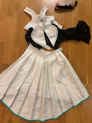 Hatsune Miku symphony cosplay - Vocaloid Hatsune Miku symphony cosplay från dokidokicosplay, har använts ett par gånger. Inkluderar kjol, tröja, hårband, vit krage, strumpor och rosett. Tanken är att rosetten ska ha en knapp som man kan fästa på kjolen, men denna har ramlat av så om man vill sätta på rosetten får man sy på en egen knapp. 