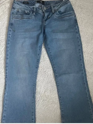 LTB ljusblå jeans W26 L32 - Säljer ett par ljusblå jeans från LTB med klassisk femficksdesign och snygga sömmar på bakfickorna. Jeansen har normal passform och är utsvängd, perfekt för dig som gillar enkel och stilren look.