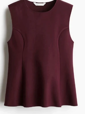 Vinröd ärmlös topp med A-linjeform - Säljer en vinröd topp med A-linjeformad siluett och rund halsringning. Toppen är ärmlös och har en stilren, minimalistisk design utan synliga detaljer. Materialet är mjukt och har lite struktur, perfekt att matcha med jeans eller kjol.