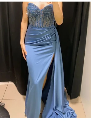 Blå festklänning med slits och paljetter - Säljer en elegant blå långklänning, glittrig med paljett och slits. Har korsett i ryggen för justering av storlek och passform. Använd en gång. Säljer för 4000kr, pris kan diskuteras. Ordinariepris 7000kr