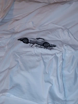 Vit Corvette t-shirt från GM XS - Säljer en vit t-shirt från GM med en stor Corvette-illustration och snygg text på bröstet. Klassisk rund hals och korta ärmar. Tillverkad i mjuk bomull, perfekt för dig som gillar bilar och vill ha en clean look.