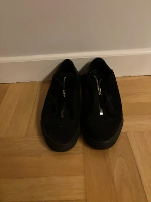 Svarta sneakers från Axel Arigato - Säljer ett par svarta sneakers från Axel Arigato i mocka med dragkjedja. Storlek 42 och inga stora fläckar eller liknande.