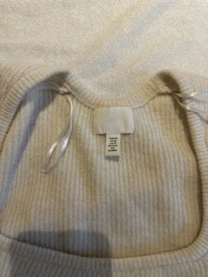 Beige ribbad stickad tröja H&M - Säljer en beige ribbad stickad tröja från H&M i storlek XS. Tröjan har en bred, fyrkantig ringning och långa ärmar. Den är croppad och har en mjuk, mysig känsla som passar perfekt till höst och vinter.