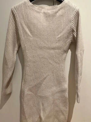 Beige ribbad stickad klänning - Säljer en beige ribbad stickad klänning från H&M i storlek XS. Tröjan har lång ärm, rund halsringning och är figurnära i modellen. Materialet är en mix av polyester, akryl och lite ull vilket gör den både mjuk och varm. Perfekt till höst och vinter! Sitter SÅ snyggt!!