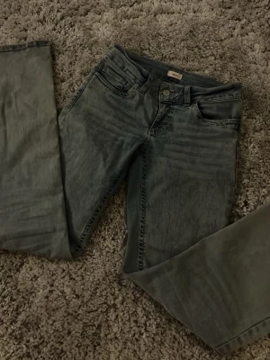 Grå slitna jeans med broderade fickor - Säljer ett var jätte snygga jeans från Nelly med håll på båda knäna. Tyvärr har dessa byxor blivit för små och för korta för mig..                                     Köpte byxorna för 700 kr. 