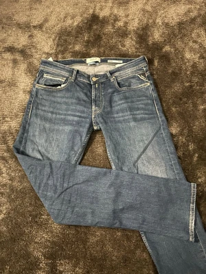 Replay Grover blå jeans straight fit - Säljer ett par klassiska blå Replay Grover jeans med straight fit. Jeansen har fem fickor, snygga kontrastsömmar och en patch med Replay-logga bak i midjan. Tillverkade i slitstarkt denim med en tidlös look som passar till det mesta.