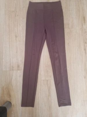 Bruna leggings från A Misu XS - Snygga chokladbruna leggings från A Misu i stretchigt och mjukt material. De har hög midja och söm framtill som ger en clean look. Perfekta att styla med oversized tröja eller hoodie för en chill vibe.