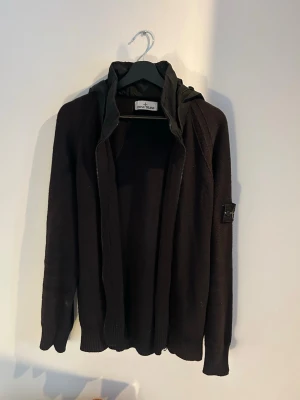 Stickad Stone Island cardigan med luva - Säljer en mycket fin stickad Stone Island-cardigan/kofta med huva i storlek L. Modellen är från  kollektion (S/S 2024). Köpt på Stone Island, kan bifoga bild på äkthetsbevis. Nypris 7300 kr.  Skick: 8/10. Använd endast ett fåtal gånger, nästintill inget slitage.  Storlek: L.  Modellnummer (Art.nr): 8015503B0.  Certilogo (CLG 759 302 091263). Går att ta bort luvan (se sista bilden) Skickas snabbt och spårbart. Hör gärna av dig vid frågor!