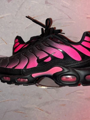 Nike Air Max Plus rosa och svarta - Köpte på jd sport Sthlm Säljer ett par Nike Air Max Plus med grymt snygg färgskiftning i rosa och svart. Skorna har mesh-överdel, svarta detaljer och synliga Air-enheter i sulan. Klassisk Tn-logga bak och svarta snören. Perfekta för dig som vill sticka ut med dina sneakers.