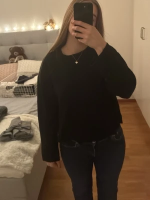 Svart stickad tröja från 157 - En enkel och stilren svart stickad tröja från 157. Tröjan har rund halsringning, lång ärm och en något loose passform. Perfekt att slänga på sig till jeans eller kjol för en clean look.