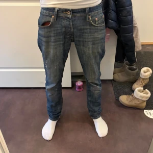Blå skinny jeans från Jack & Jones - Säljer ett par blå skinny jeans från Jack & Jones med slitningar och hål på vänster lår. Klassisk femficksmodell med normal midja och snygga tvättade detaljer. passformen är slim/glenn